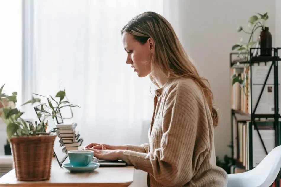 A young woman sitting at a table using Marky on her laptop.